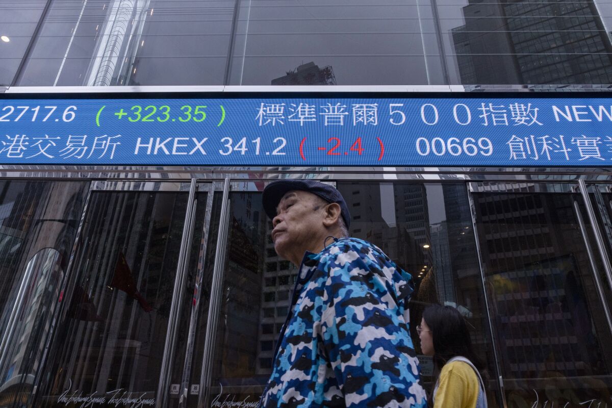 A pedestrian passes by the Hong Kong Stock Exchange electronic screen in Hong Kong, Thursday, March 30, 2023. Asian shares were mixed Thursday following a rally on Wall Street as worries over banks following the collapses of several lenders in recent weeks eased further. (AP Photo/Louise Delmotte)