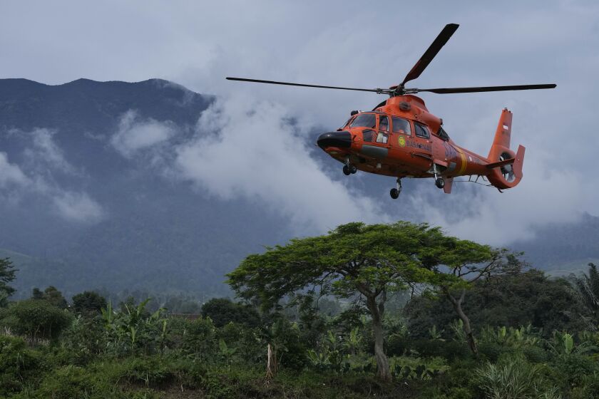 Members of the National Search and Rescue Agency (BASARNAS) flies a helicopter to deliver relief goods to a village affected by Monday's earthquake in Cianjur, West Java, Indonesia, Saturday, Nov. 26, 2022. The magnitude 5.6 quake killed hundreds of people, many of them children, and displaced tens of thousands. (AP Photo/Achmad Ibrahim)