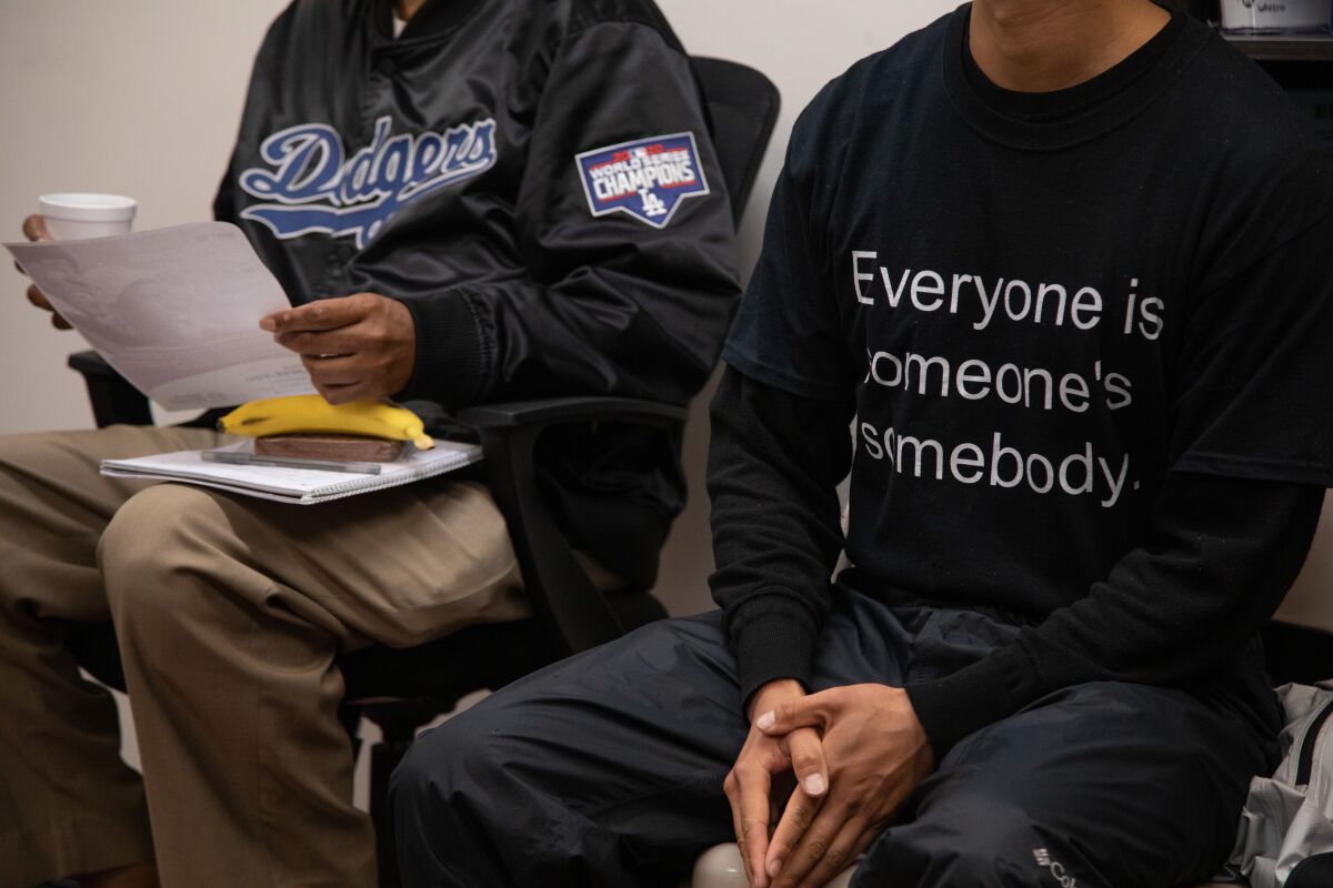 John Ma wears the company's motto on his shirt, Everyone is someone's somebody, while sitting next to another person.