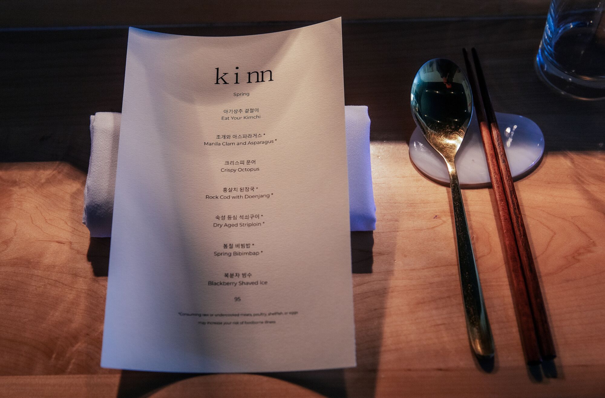 A table setting and menu is placed on the counter at Kinn, a small tasting menu restaurant on 6th St. in Koreatown.
