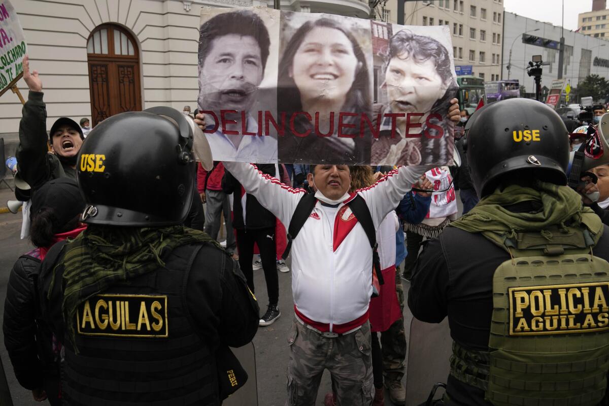 Un opositor al gobierno del presidente Pedro Castillo sostiene fotografías de Castillo