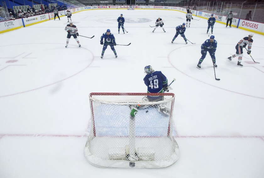 Edmonton Oilers' Connor McDavid, far right, scores against Vancouver Canucks goalie Braden Holtby (49) during the second period of an NHL hockey game, Monday, May 3, 2021, in Vancouver, British Columbia. (Darryl Dyck/The Canadian Press via AP)
