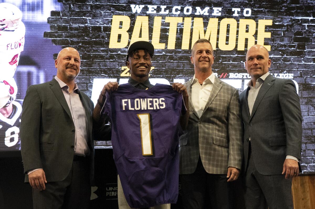 Joe Hortiz, Zay Flowers, John Harbaugh and Eric DeCosta under a "Welcome to Baltimore" banner.