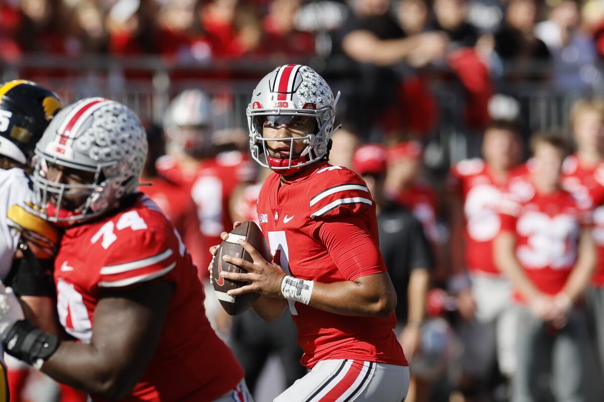 Ohio State quarterback C.J. Stroud holds the ball while players are to the left of him and behind him..