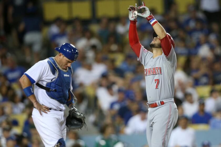 Reds shortstop Eugenio Suarez points to the sky after crossing the plate on his three-run home run while Dodgers catcher A.J. Ellis looks at the ground at Dodger Stadium on Aug 13.