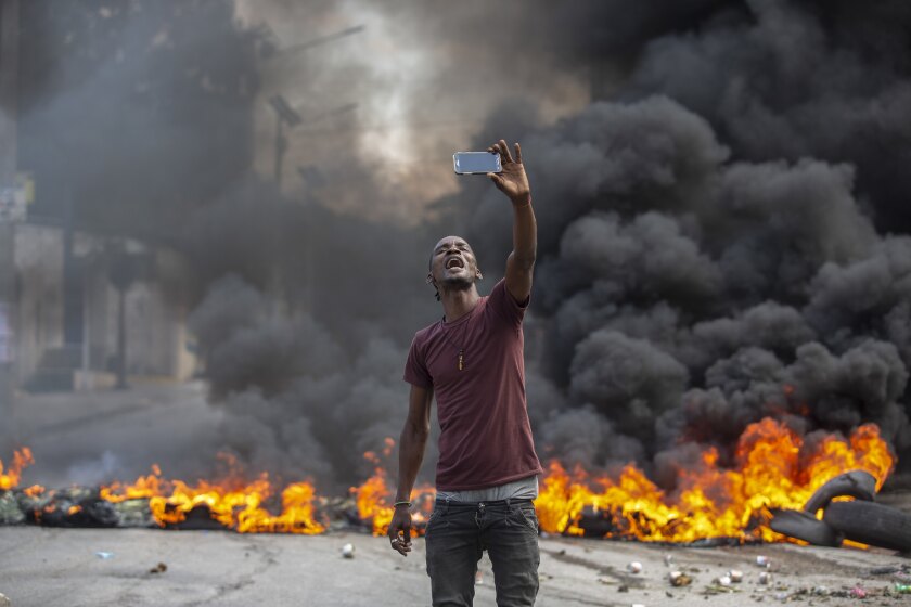 Un manifestante se toma una selfie en una barricada en llamas