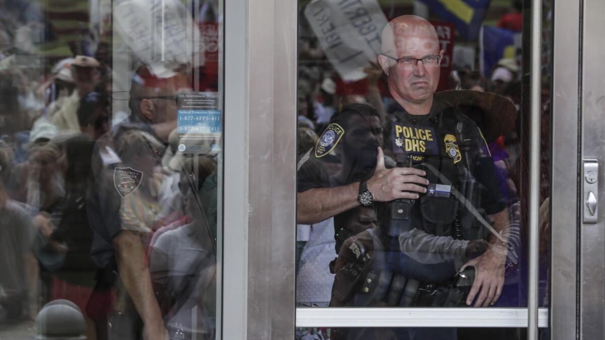 A Department of Homeland Security police officer watches protest outside the federal courthouse in Brownsville, Texas, on Thursday.