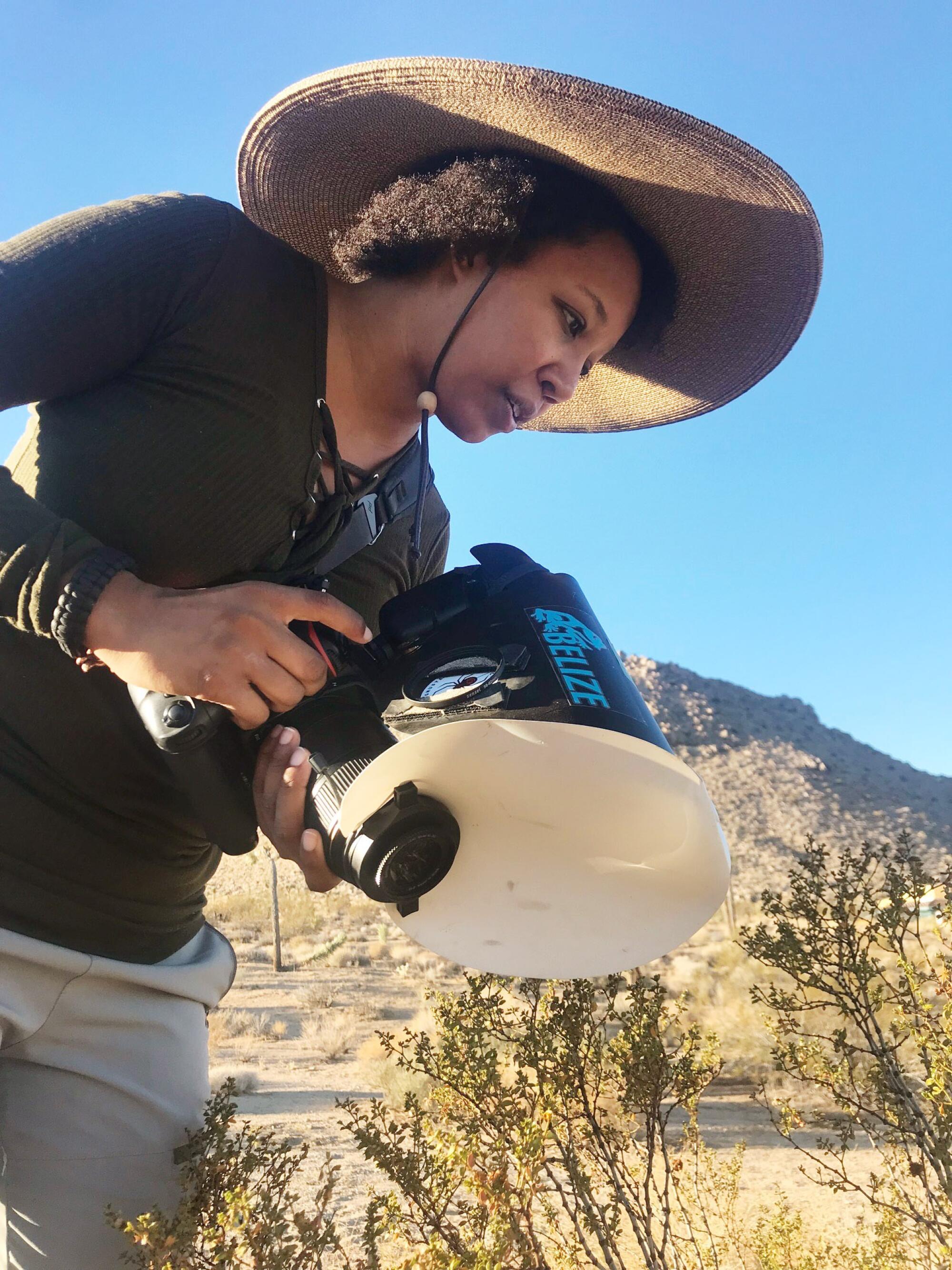 Krystle Hickman, wearing a broad-brimmed hat to protect her skin, searches for native bees.