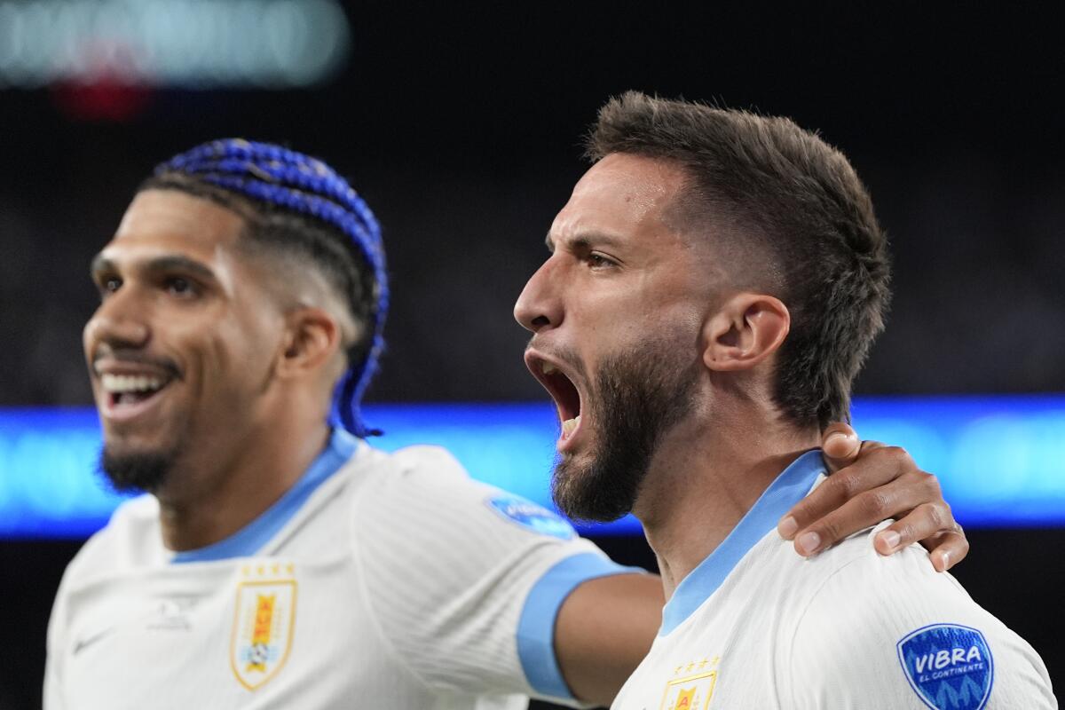 Rodrigo Bentancur (derecha) celebra con Ronald Araujo tras anotar el quinto gol de Uruguay en la victoria