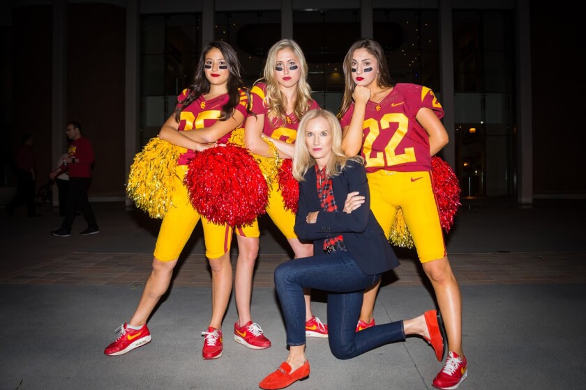 Former USC Song Girls coach Lori Nelson kneels in front of three dancers