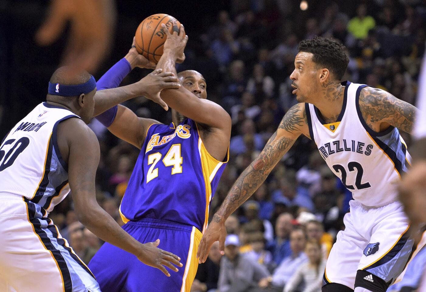 Kobe Bryant looks to pass while being defended by Grizzlies forwards Zach Randolph and Matt Barnes (22) during the first half of a game on Feb. 24.