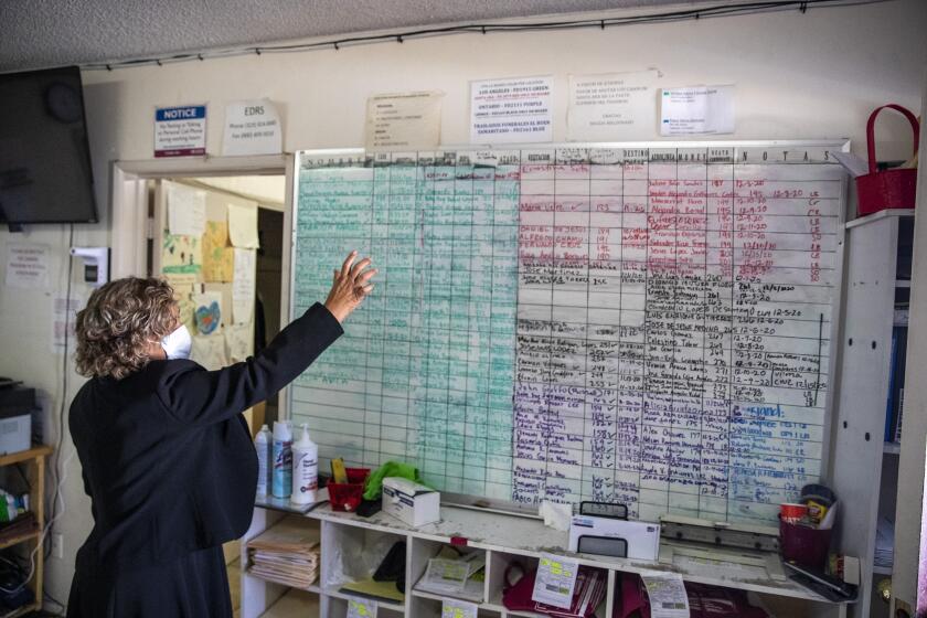EAST LOS ANGELES, CA - DECEMBER 20: Continental Funeral Home Director Magda Maldonado looks over a board with dozens of names of the dead who have not yet been buried or cremated on Sunday, Dec. 20, 2020 in East Los Angeles, CA. (Brian van der Brug / Los Angeles Times)