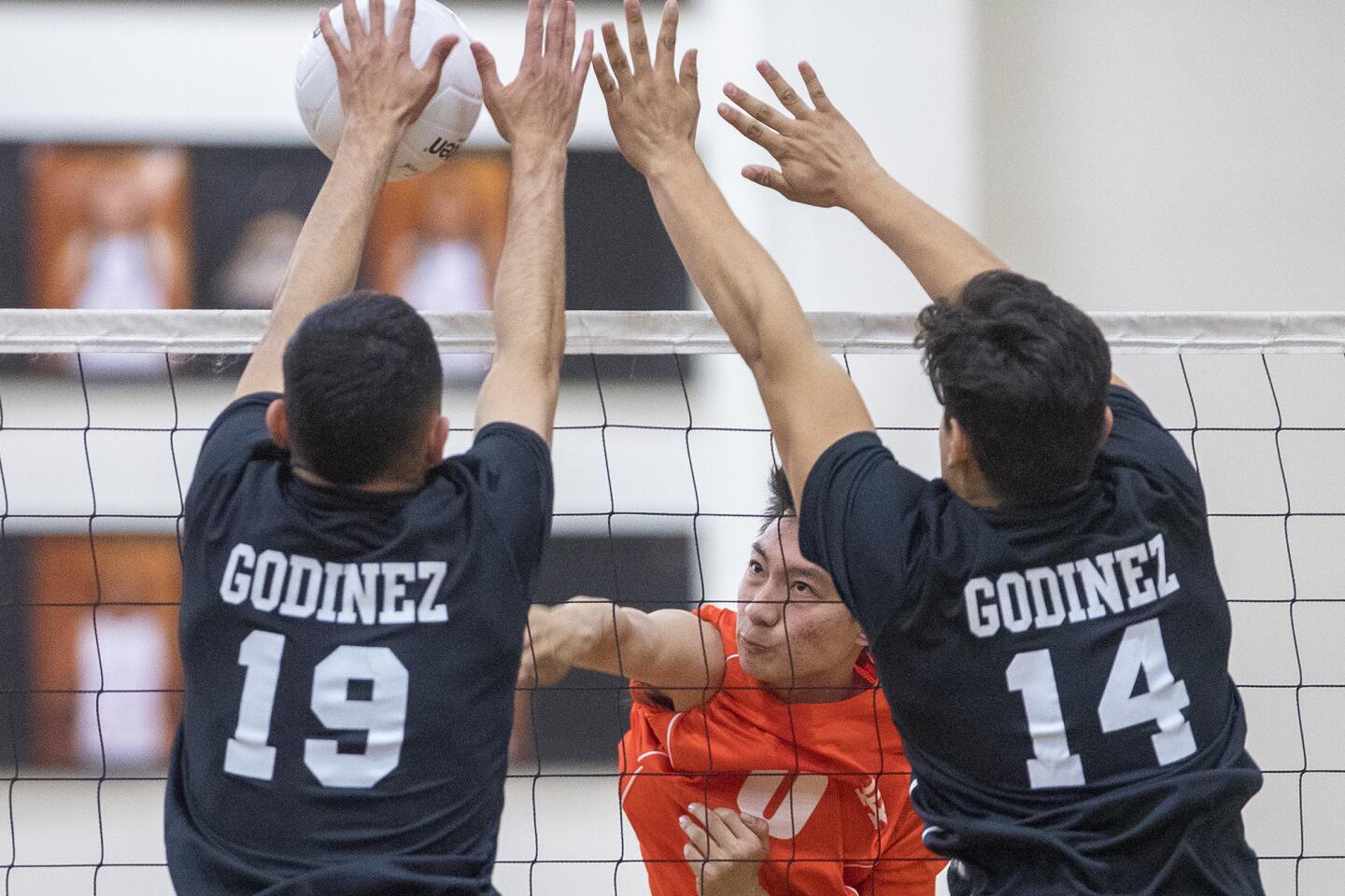 Los Amigos's Andrew Nguyen hits into Godinez's Angel Zavala, 19, and Larry Perea, 14, during a match on Friday, March 3.