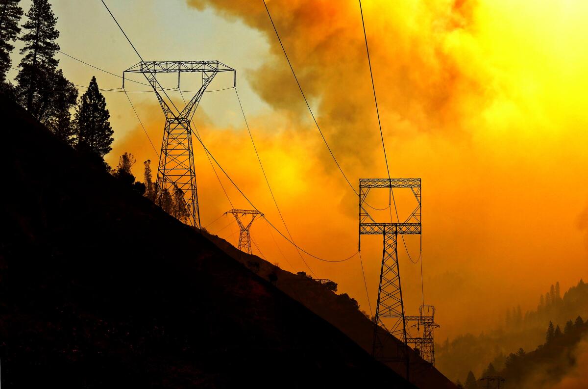 Red skies and smoke loom over power lines on a hillside