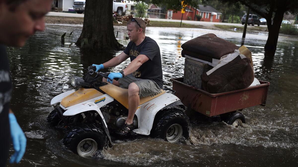 Mike and Matt Wroten clean out Mike's waterlogged home Friday in St. Amant, La.