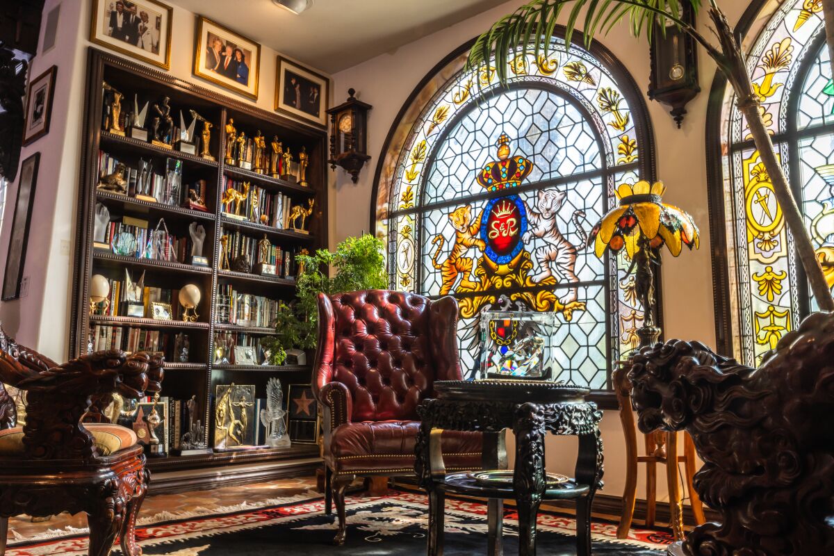 Big chairs and stained glass beside a bookcase.