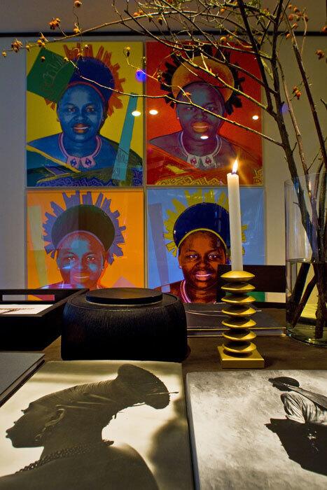 A dining room art composition: On the wall are four Queen Ntombi paintings by Andy Warhol. Instead of flowers, the white vase holds rose hips. The books are "Lost Africa" by Casimir Zagourski and "Small Trades" by Irving Penn.