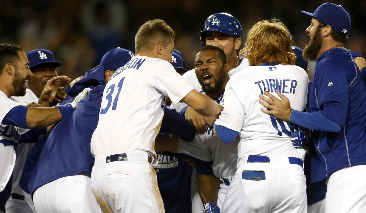 Howie Kendrick is mobbed by his teammates after delivering a walk-off victory for the Dodgers with a two-run single in the bottom of the ninth inning. The Dodgers beat the Mariners, 6-5.