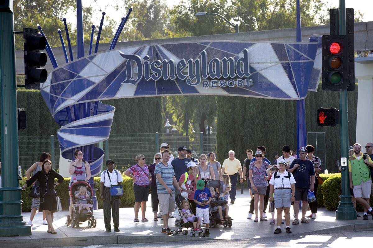 Disneyland patrons exit the park under the Disneyland sign.