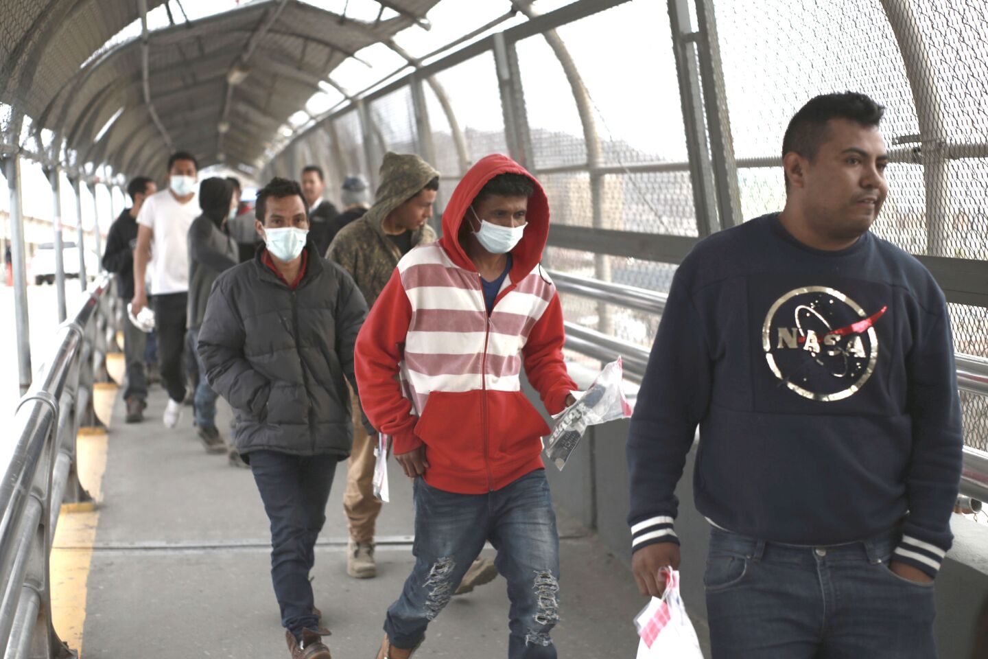 Mexico: Central American migrants seeking asylum, some wearing protective face masks, return to Mexico via the international bridge at the U.S-Mexico border.