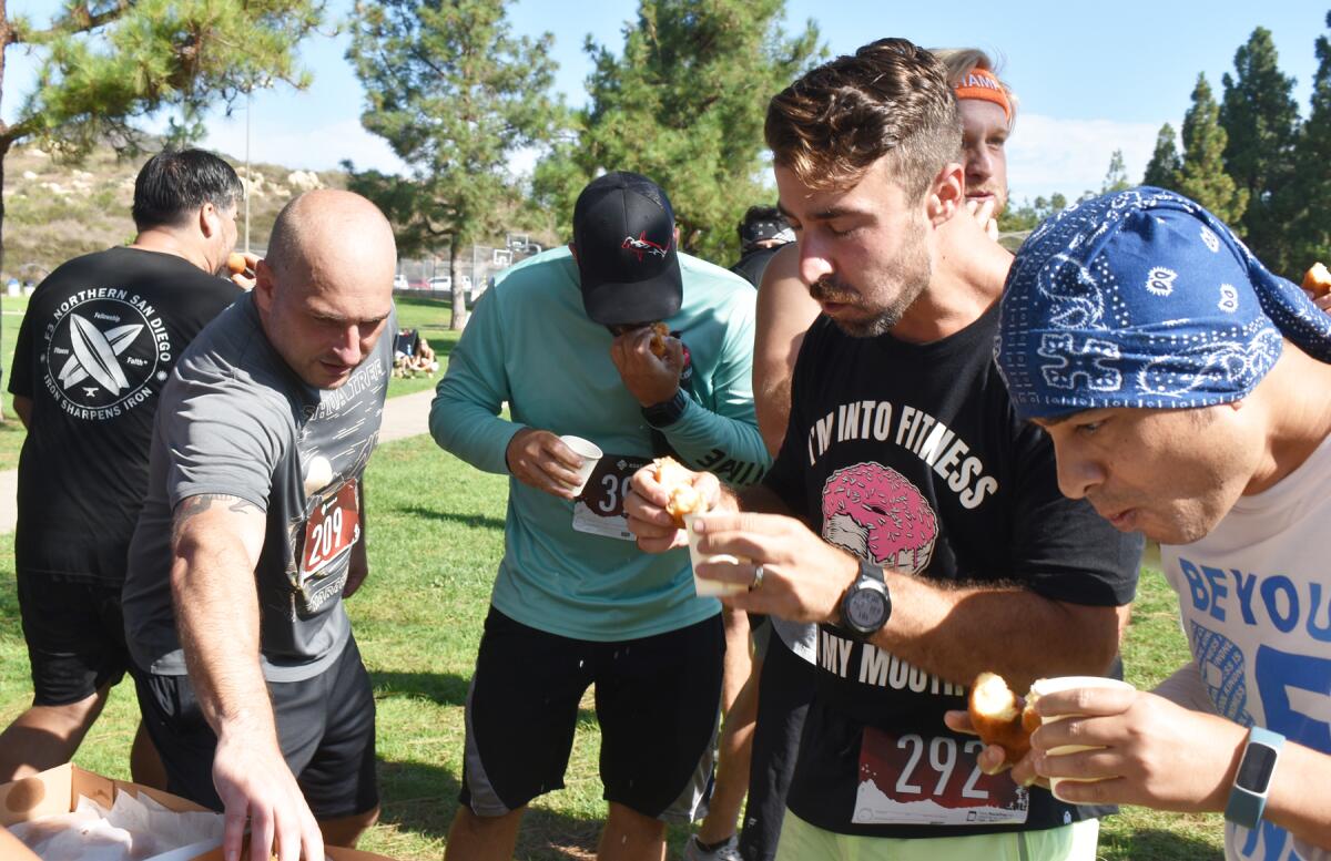 Donut Mile runners eating their first of four doughnuts during the mile-long race.