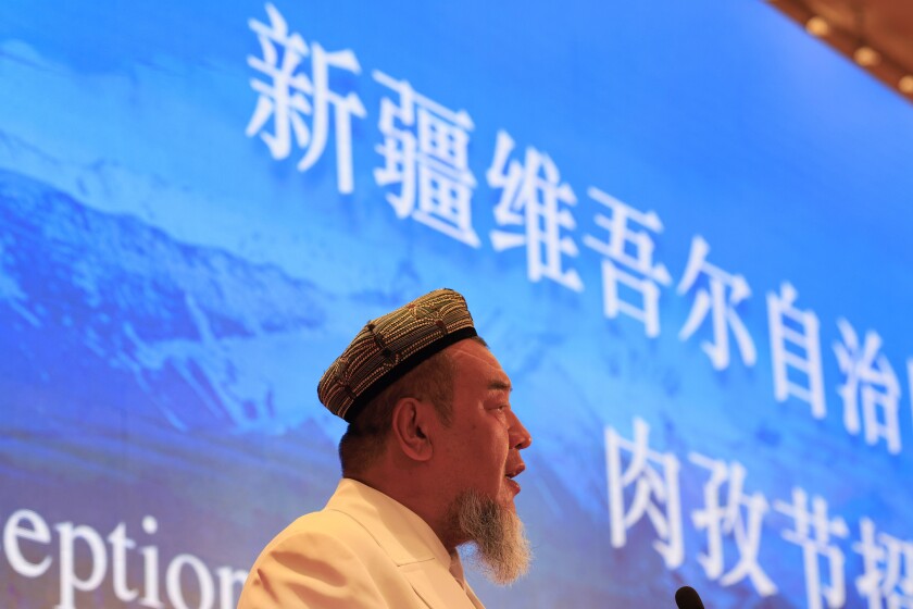 Abdureqip Tomurniyaz, who heads the association and the school for Islamic studies in Xinjiang, speaks during a government reception held for the Eid al-Fitr festival in Beijing on Thursday, May 13, 2021. Muslim leaders from the Xinjiang region rejected Western allegations that China is suppressing religious freedom, speaking at a reception Thursday for foreign diplomats and media at the end of the holy month of Ramadan. Chinese characters at top reads Xinjiang Uyghur Autonomous Region. (AP Photo/Ng Han Guan)