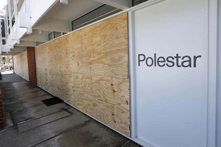 Plywood covers the Polestar car showroom window panes where a man smashed through the windows, caused damage to the showroom, and stole one of the cars in the process over the weekend in Laguna Beach.