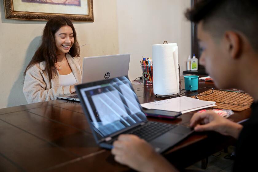 LOS ANGELES, CA - DECEMBER 11: Stephanie Contreras-Reyes, 17, a senior at Orthopaedic Hospital Medical Magnet High School, attends an online Principles of American Democracy class, while her brother Ismael Contreras-Reyes, 13, works on algebra, at their home on Friday, Dec. 11, 2020 in Los Angeles, CA. Contreras-Reyes, who does it all - helps her younger siblings with classes, leads her own club, and works with her mom Teresa Reyes at an embroidery factory. An increasing number of high schoolers have started working more hours - or working for the first time - to keep their families afloat. (Gary Coronado / Los Angeles Times)