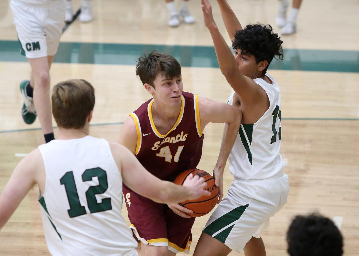 Estancia's Jake Covey drives to the basket and into the defense of Costa Mesa's Joe Paxson (12) and Gio Quero (11) during an Orange Coast League game on Wednesday.