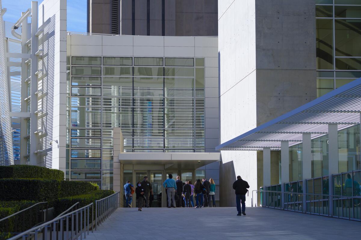 People wait to enter a modern courthouse building. 