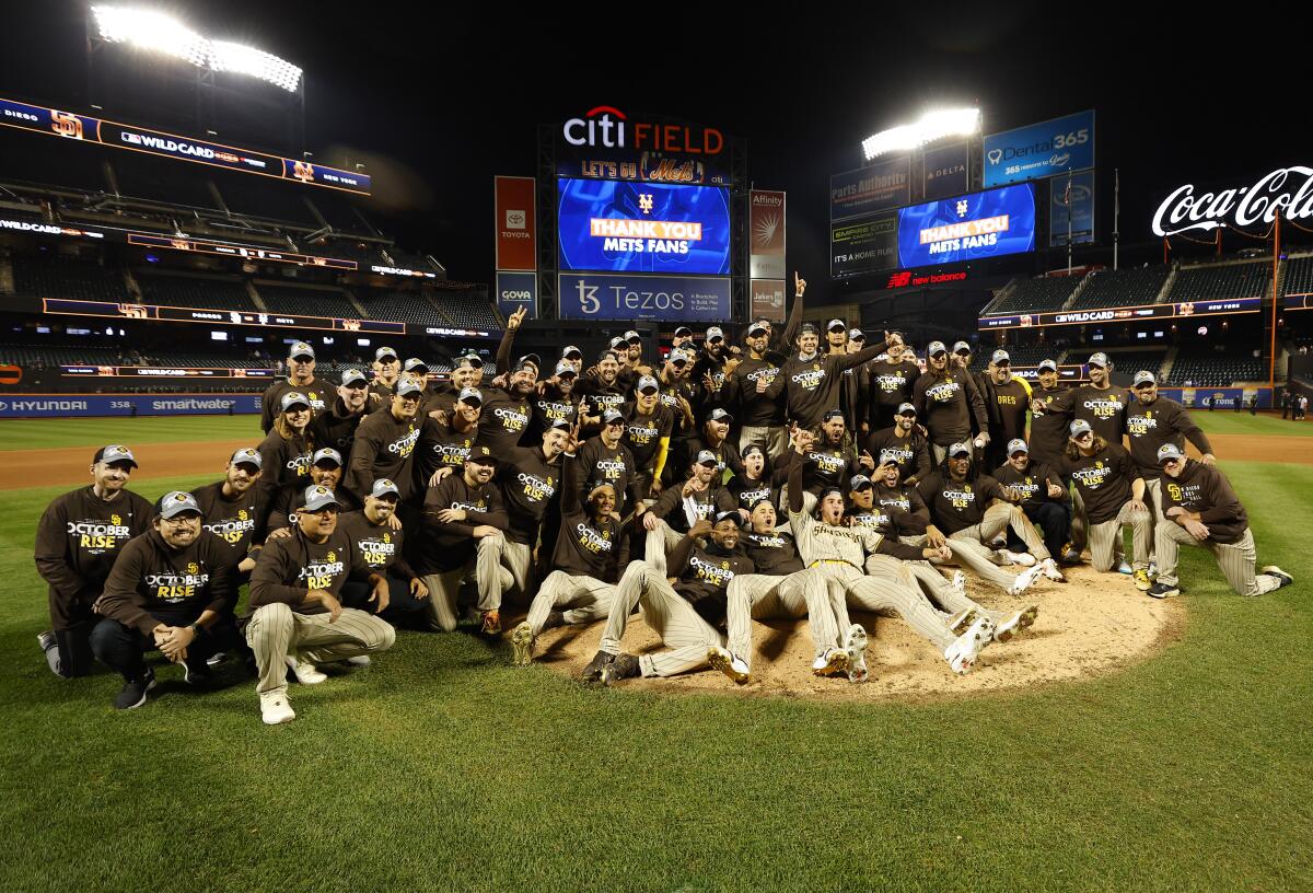 The Padres celebrate beating the Mets in an NL wild-card series Sunday with a team photo at Citi Field in New York.
