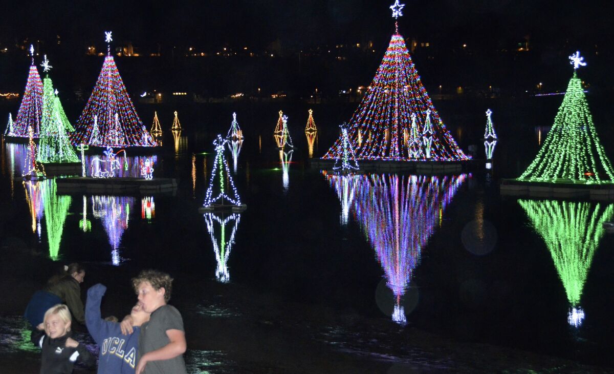 Kids pose for photo in front of the floating trees on the water during the Lighting of the Bay holiday celebration.