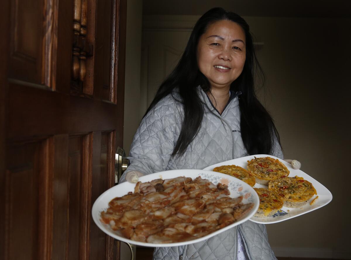 After several hours of hard work, Hue Phan displays some of the finished dishes of barbecue pork and "mam chung" that she will package for delivery. (Mark Boster / Los Angeles Times)