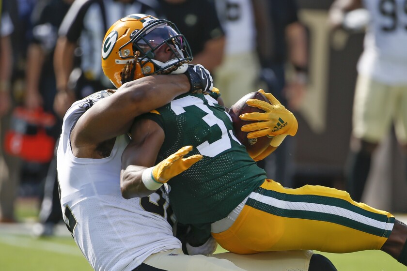 Green Bay Packers running back Aaron Jones, right, is stopped by New Orleans Saints defensive end Marcus Davenport, left, during the first half of an NFL football game, Sunday, Sept. 12, 2021, in Jacksonville, Fla. (AP Photo/Stephen B. Morton)