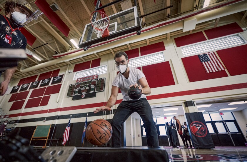 Director Jeremiah Zagar checks equipment while Juancho Hernangomez dribbles basketballs.