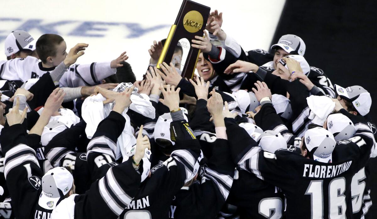 Providence players reach for the championship trophy as they celebrate their 4-3 victory over Boston University in the NCAA hockey championship game in Boston on Saturday.