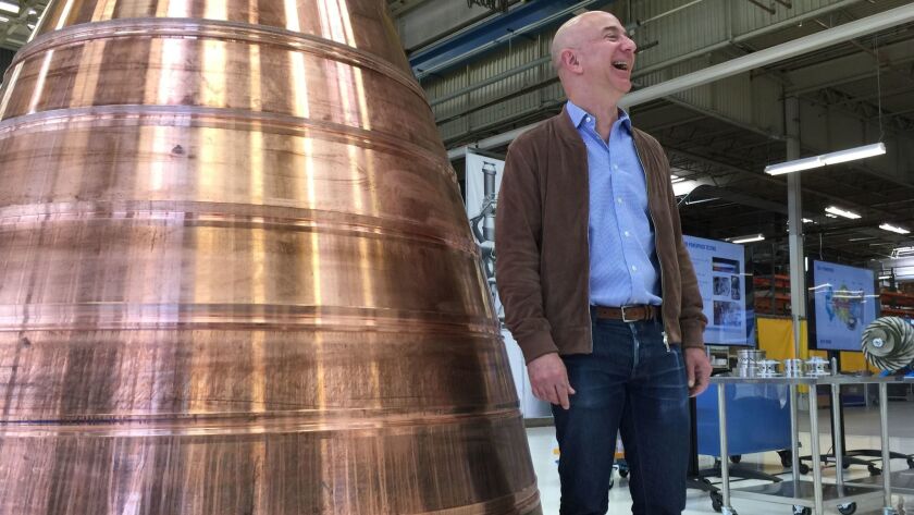 Amazon.com founder Jeff Bezos stands next to a copper exhaust nozzle to be used on a spaceship engine during a media tour of Blue Origin, the space venture he founded.