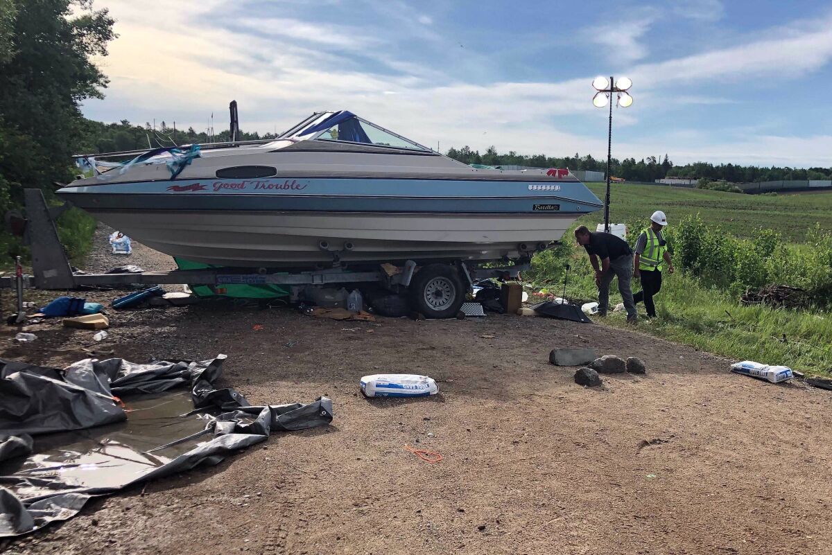 Security guards check on protesters under a boat blocking an entrance to an Enbridge Line 3 pumping station near Park Rapids, in northern Minnesota, Tuesday June 8, 2021. (AP Photo/Dave Kolpack)