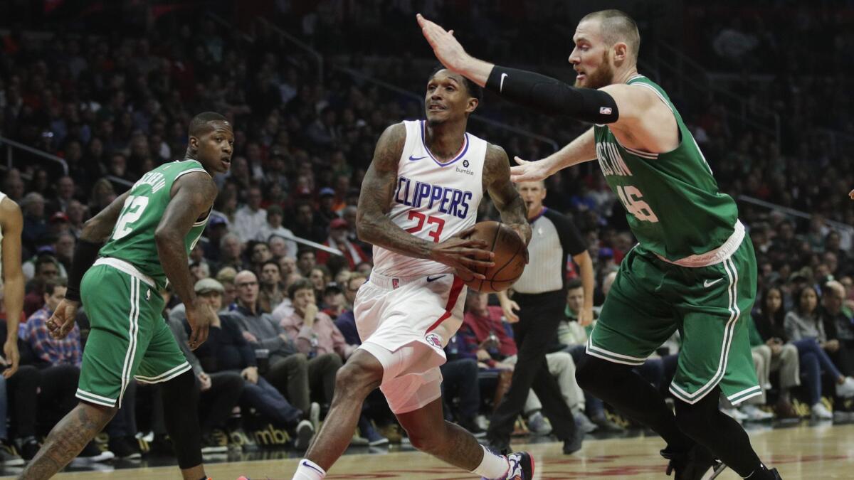 Clippers' Lou Williams, center, drives to the basket while defended by Boston Celtics' Aron Baynes during the first half.