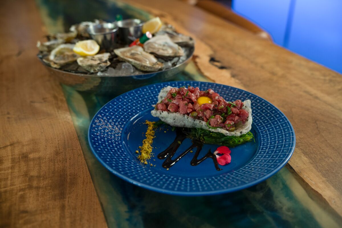 Ahi tuna tartare tostada, foreground, and a raw oyster plate at Saltwater Seafood and Steak.