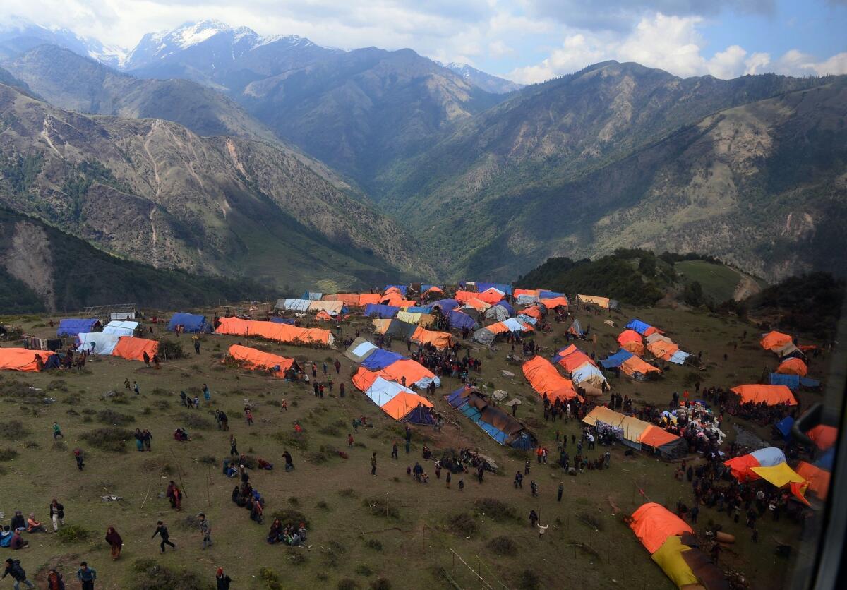 Nepalese villagers walk near their makeshift tents at Laprak village in Gorkha district in Nepal on Monday.