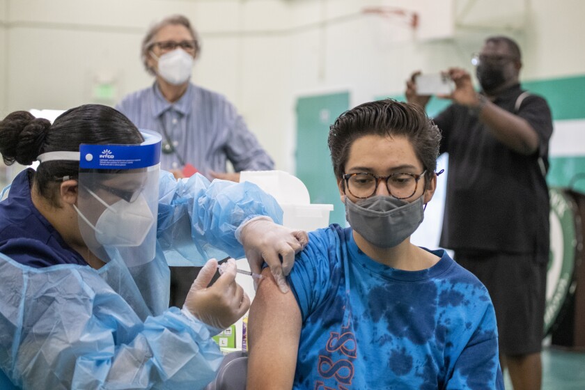 A nurse in protective gear gives a COVID-19 vaccine