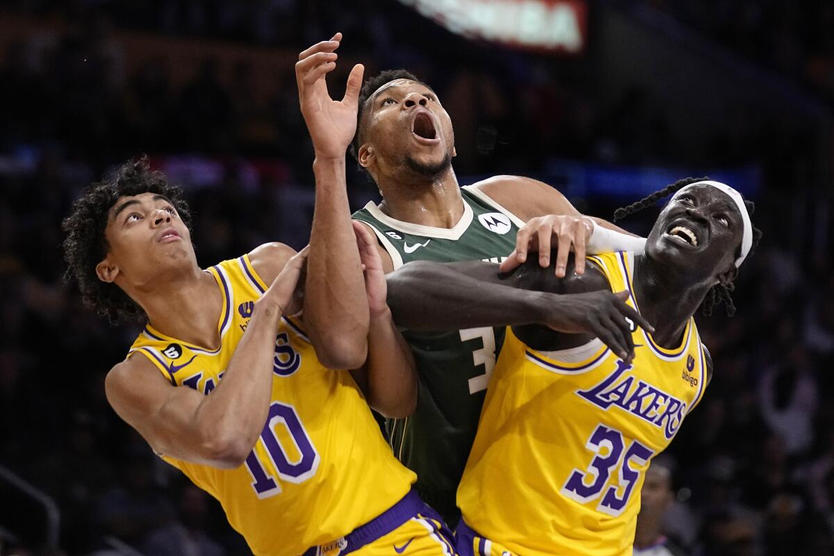 Milwaukee Bucks forward Giannis Antetokounmpo battles for a rebound with Lakers' Max Christie and Wenyen Gabriel.
