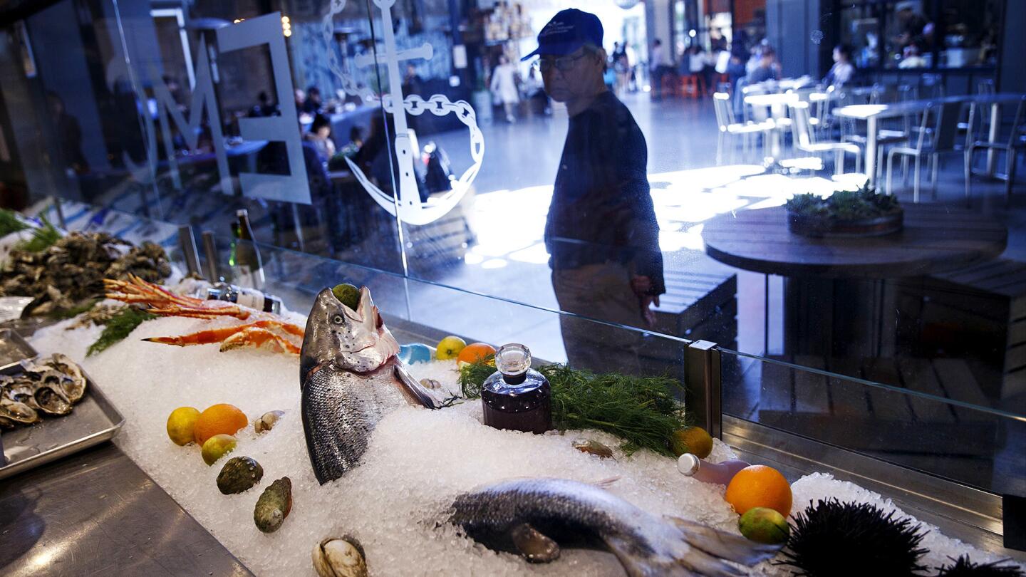 A man checks out a whole salmon on ice at the EMC Seafood & Raw Bar in the new food court of the Westfield Santa Anita mall on March 24, 2017, in Arcadia. The mall has brought in a variety of Asian retailers and restaurants to appeal to the local Asian community as well as tourists.