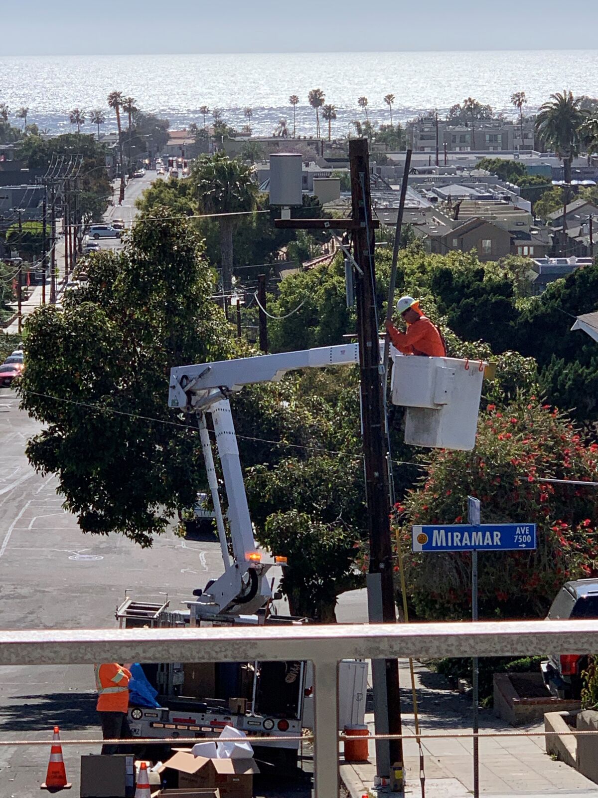 AT&T employees install a 5G miniature tower on a pole in front of La Jolla resident Harris Cohen’s house.