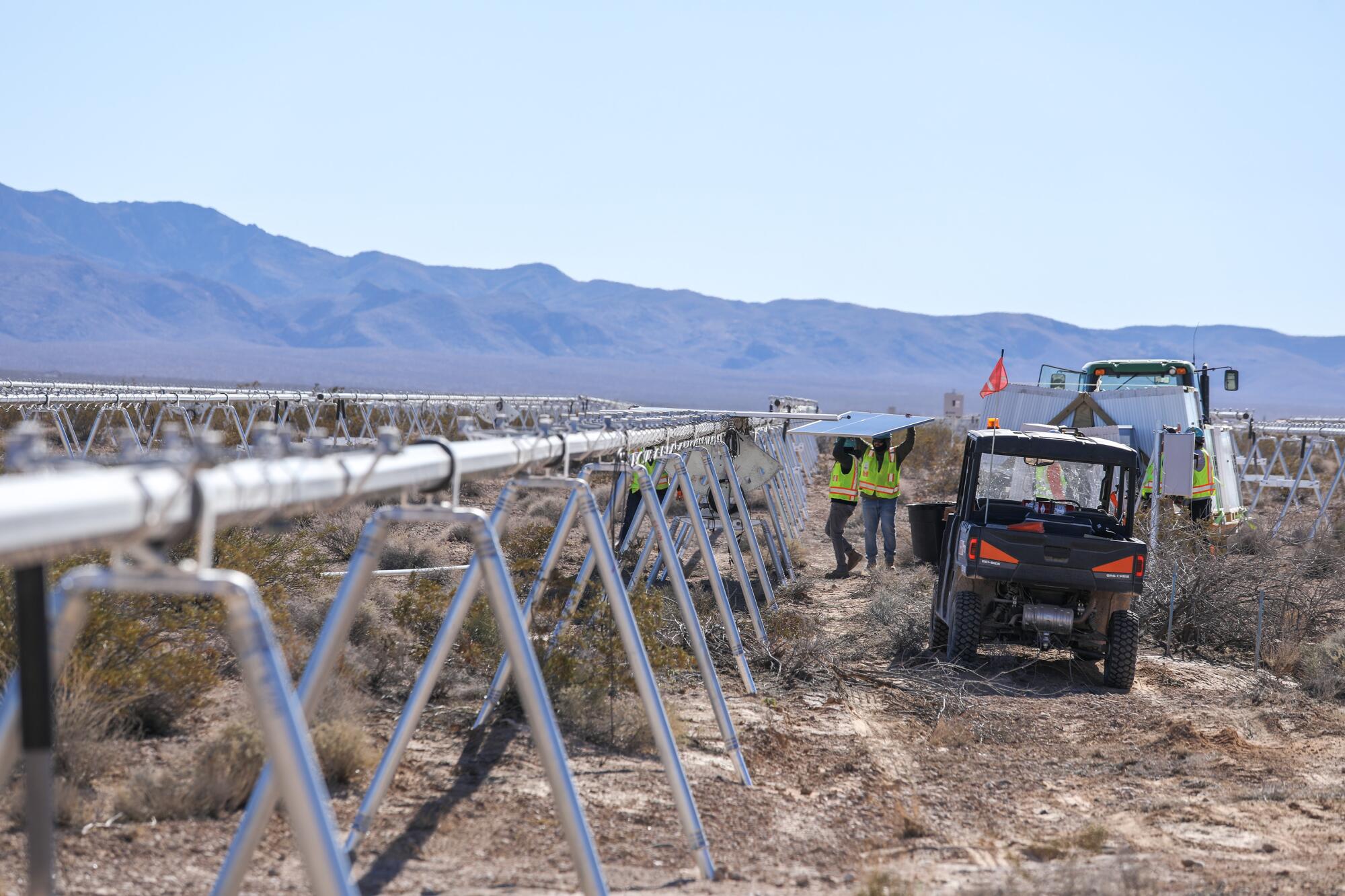 Construction workers carry photovoltaic panels for installation at the Gemini solar project in southern Nevada.
