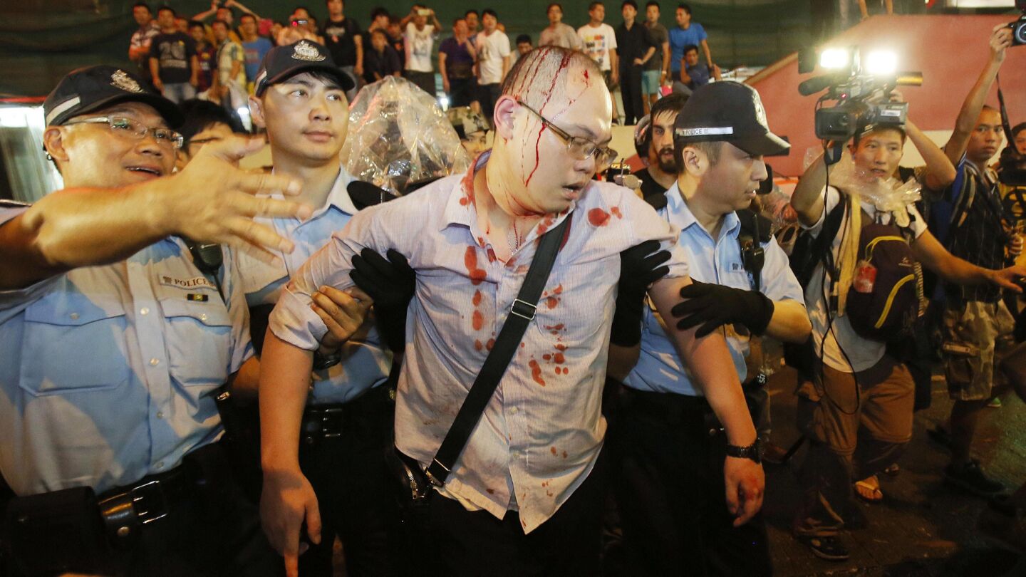 Police take an injured man from the confrontation of pro-democracy student protesters and angry local residents in Mong Kok, Hong Kong, on Friday.