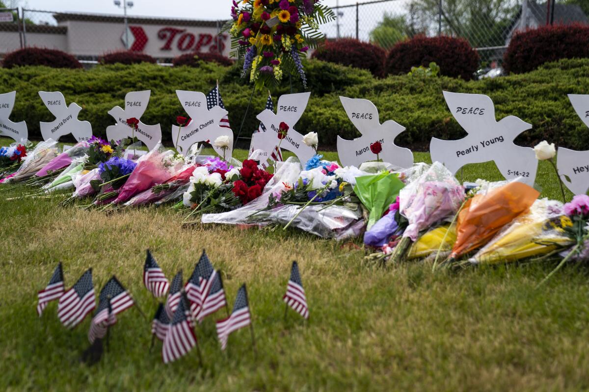 Flowers and flags dot a memorial sitting in grass