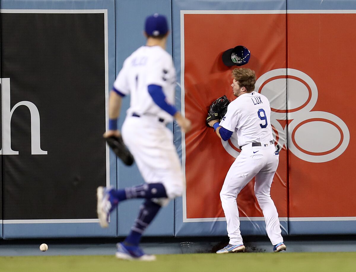 Dodgers second baseman Gavin Lux runs into the outfield wall after missing a catch.