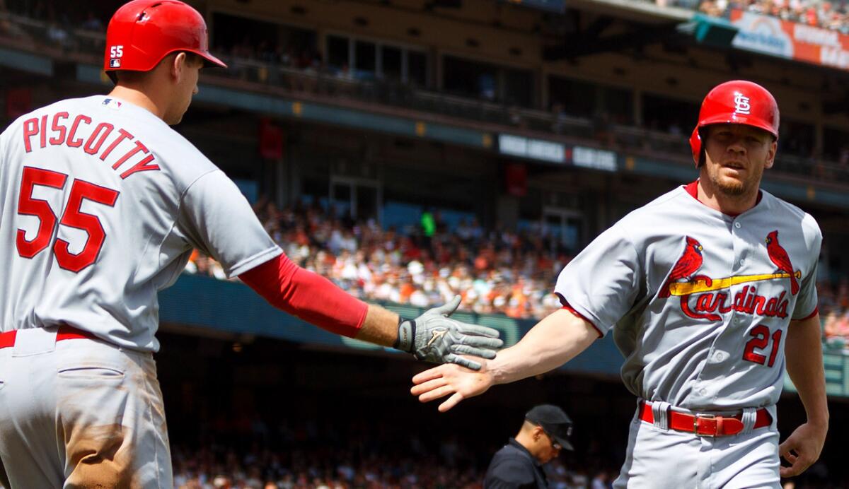 Cardinals first baseman Brandon Moss is congratulated by left fielder Stephen Piscotty, who had four hits, after scoring a run during a 6-0 victory over the Giants on Saturday.